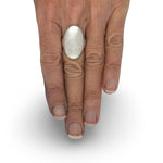 A large oval signet ring in Silver on hand. Handcrafted By Raw Jewelry Designs
